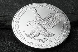 American Eagle Silbermünze 1oz 2023 als US-amerikanischer Anlageklassiker Silbermünze mit Abbild eines Adlers mit ausgebreiteten Flügeln im Anflug. Er trägt einen Ast in seinen Krallen. Die Münze liegt auf einem dunkelgrauen Hintergrund aus Stein.
